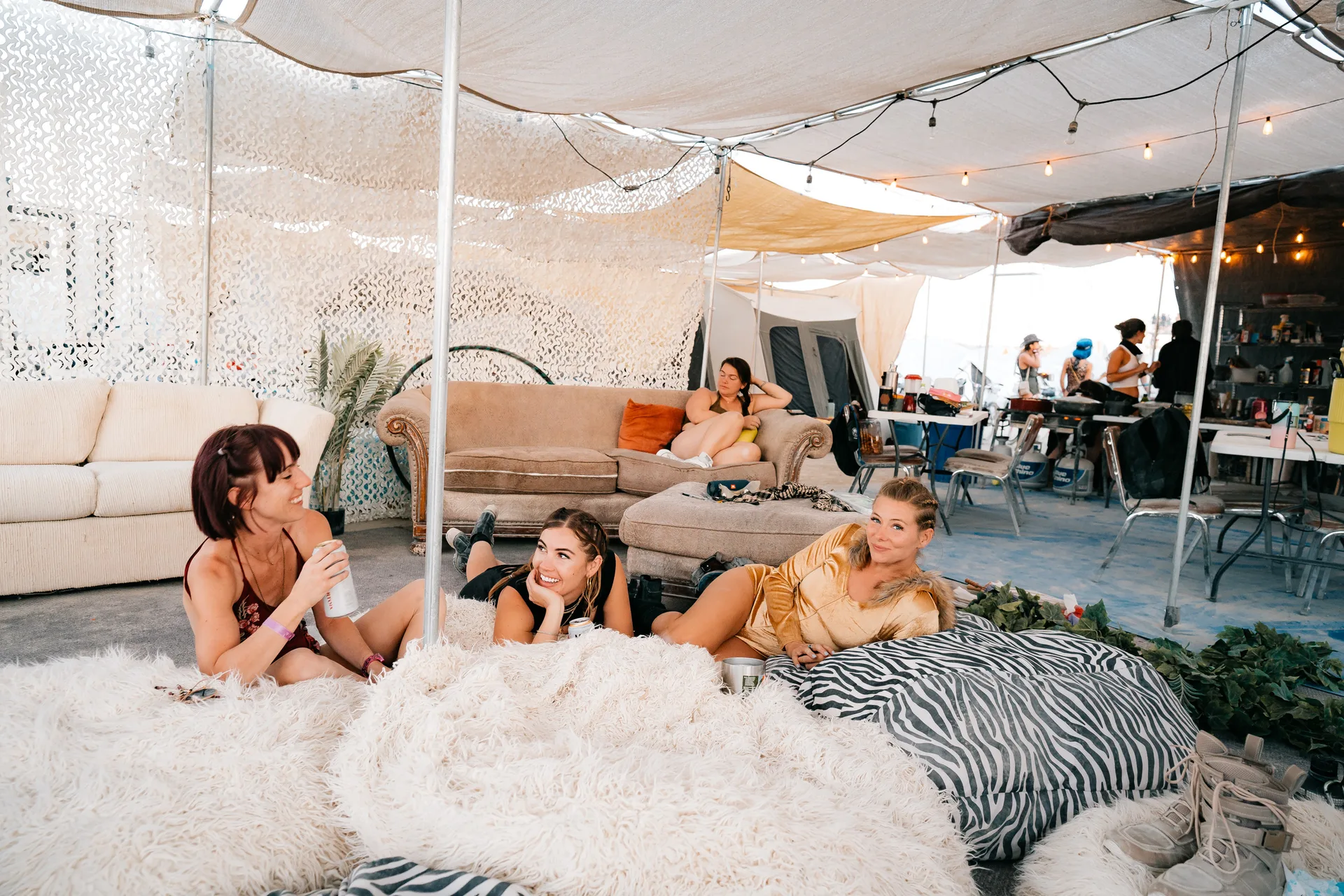 Campers relaxing on fur rugs and couches in the Muse lounge